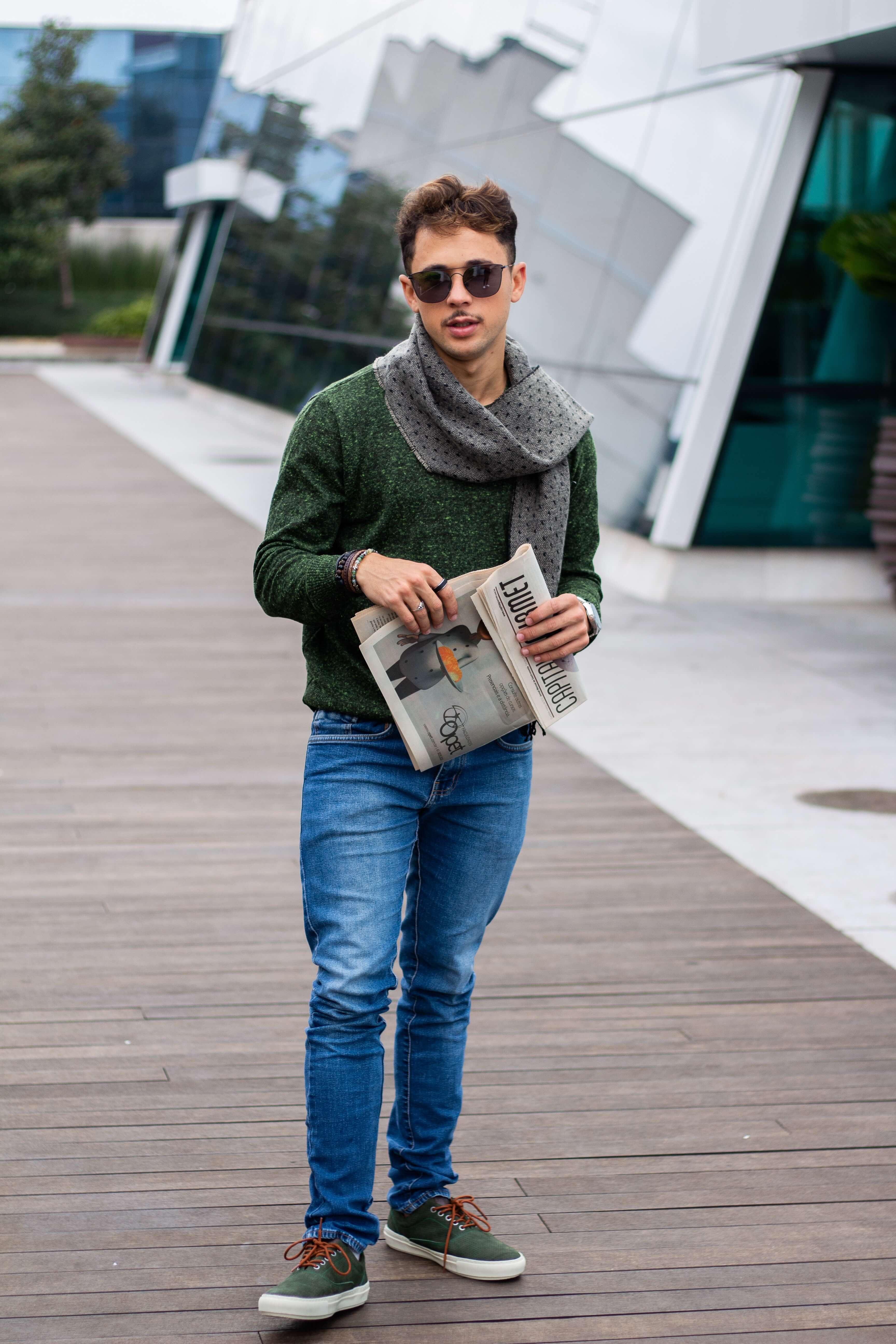 Un élève se tient sur le campus avec son journal