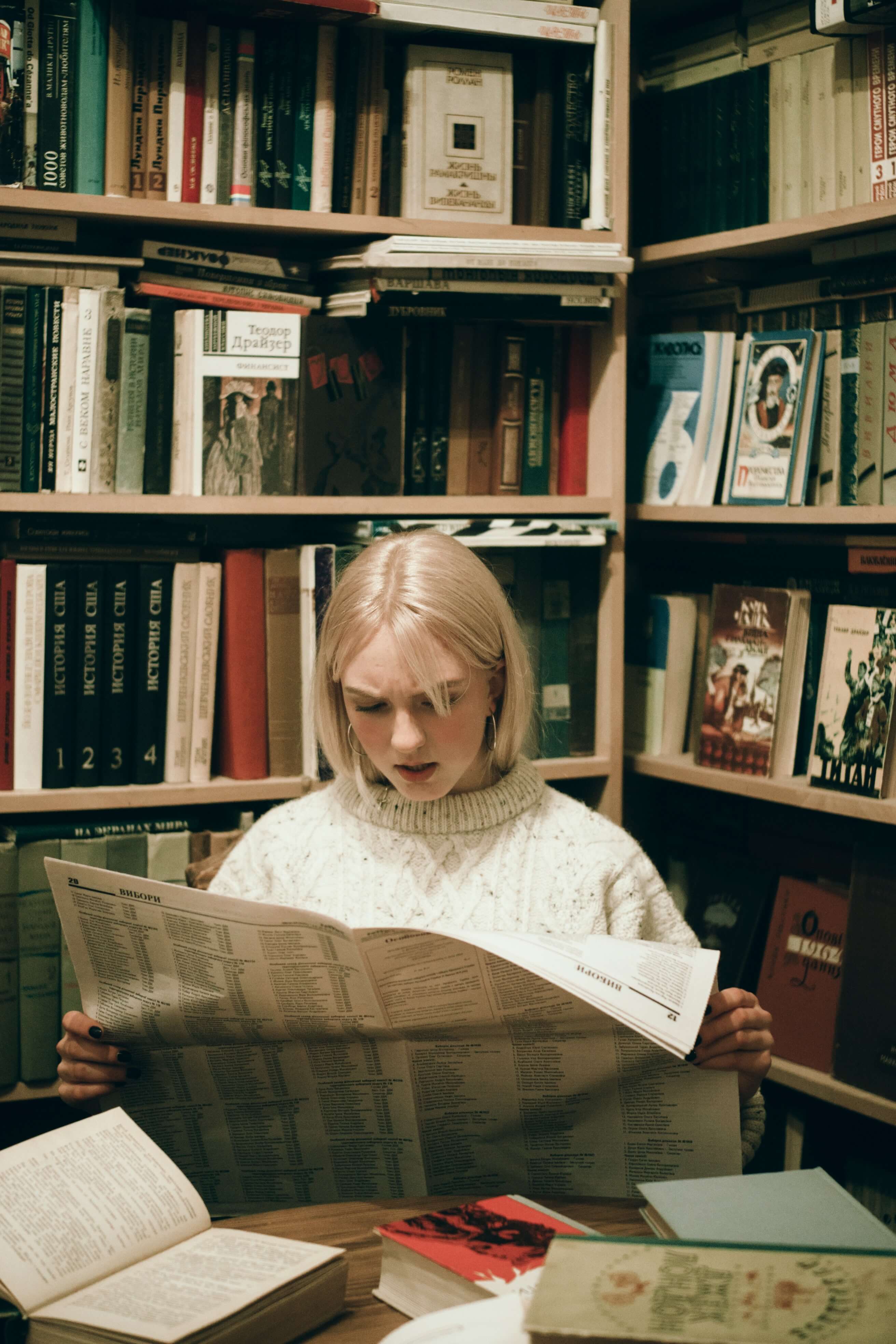 Schülerin liest Zeitung in Bibliothek