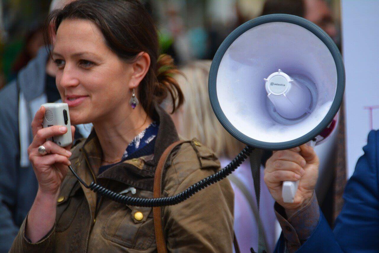 Une femme avec un mégaphone fait de la publicité électorale pour votre parti