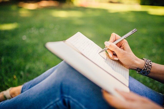 Femme écrivant sur papier dans un parc